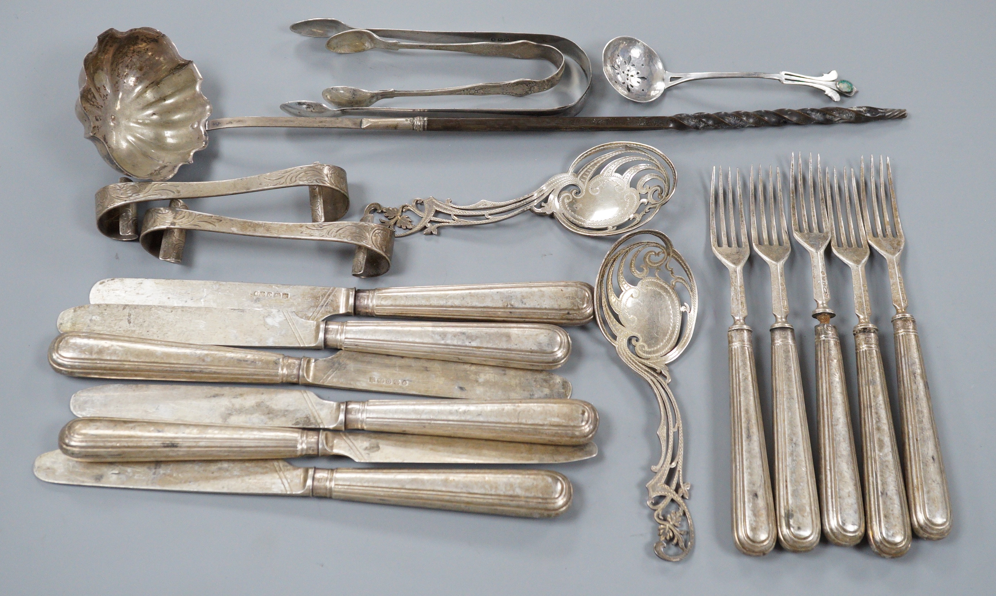 A pair of Victorian silver scrolling knife rests, George Adams, London, 1859, 10.4cm, a pair of pierced silver spoons, two pairs of silver sugar tongs, a part set of Victorian silver dessert eaters(6 & 5), a toddy ladle